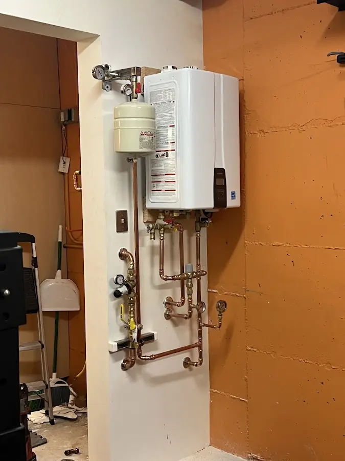 Plumbing technician inspecting water heater connections in Kurtistown